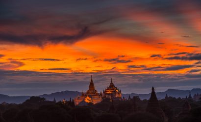 Golden temples and pagodas of Bagan silhouetted against a dramatic orange sunset sky in Myanmar.