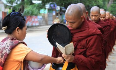 Buddhist monks receiving morning alms from local devotees in Myanmar