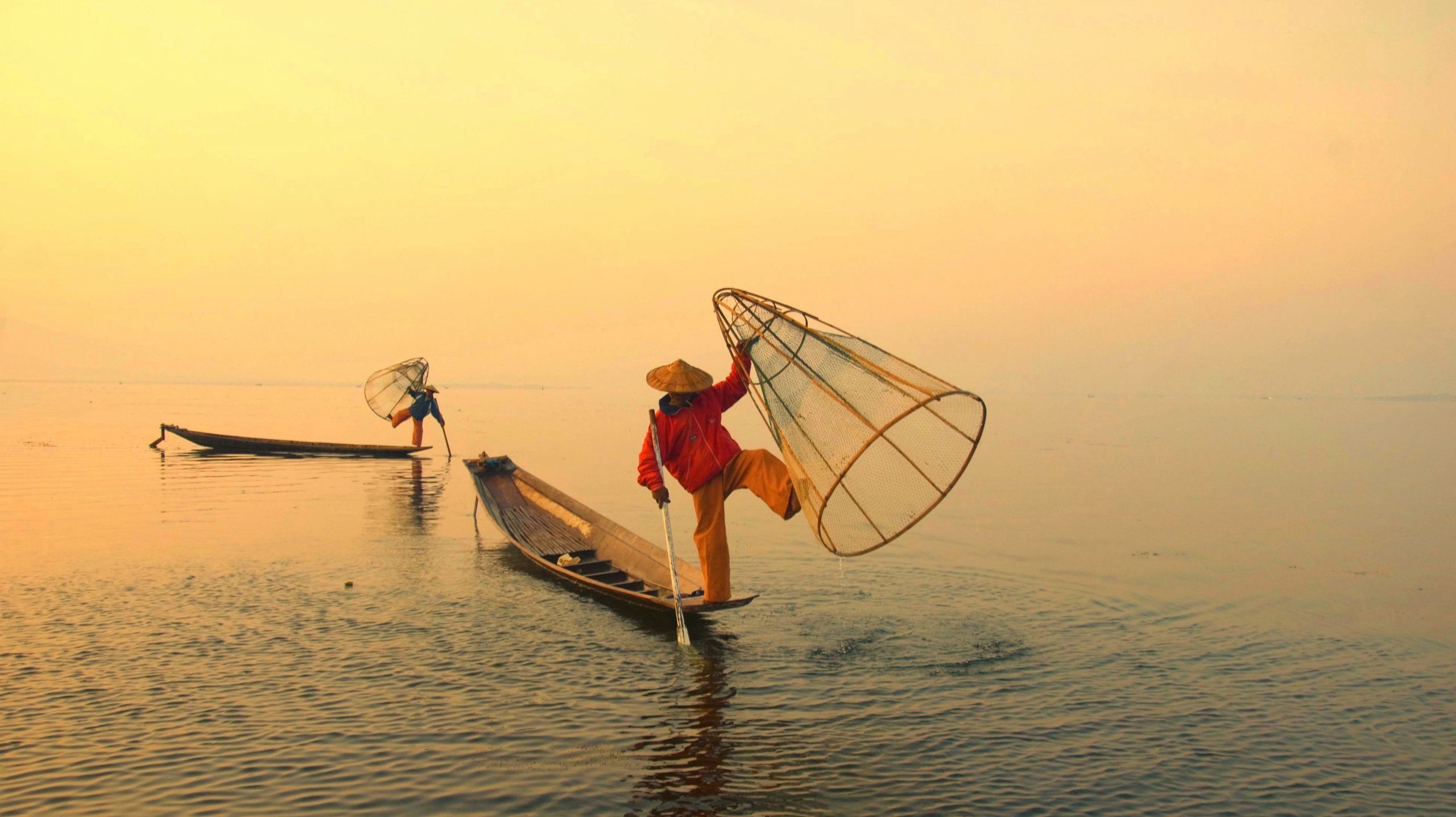 Traditional Inle Lake fishermen balancing on boats at sunrise in Myanmar cultural photography tour