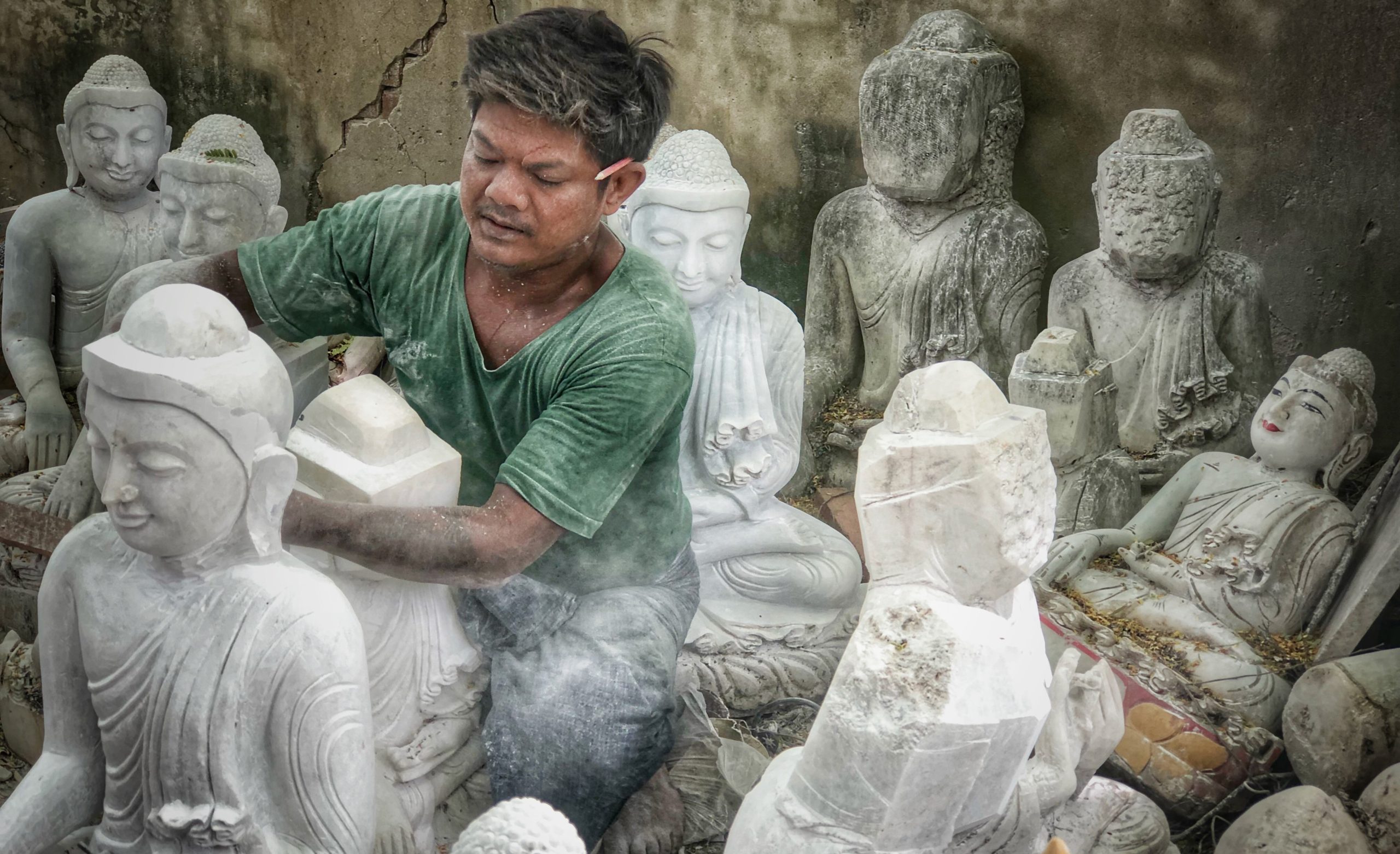 Stone sculptor carving a marble Buddha statue on Mandalay Marble Street, Myanmar.