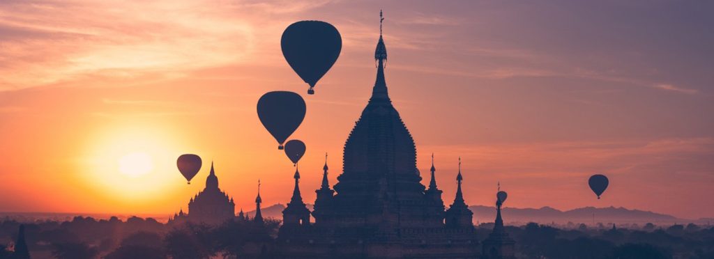 Hot air balloons floating over ancient temples in Bagan, Myanmar during a colorful sunrise.