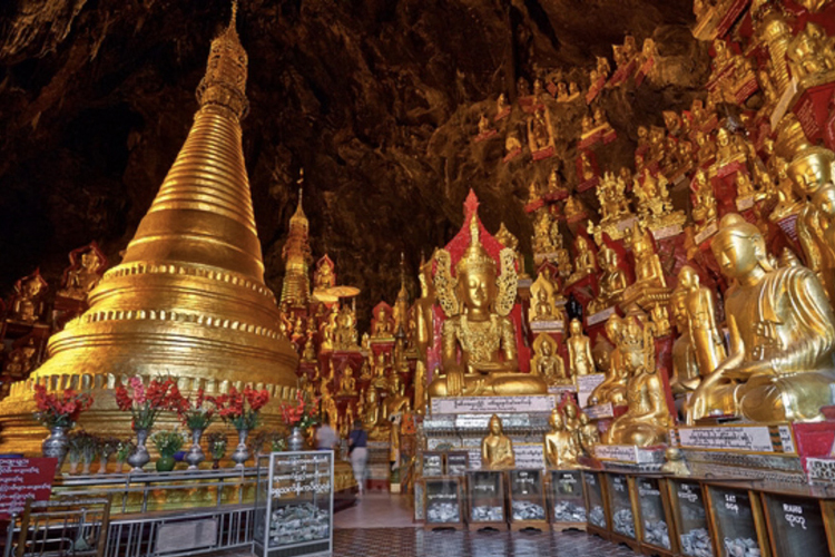 Interior of Shwe Oo Min (Pindaya) Cave with a golden stupa surrounded by hundreds of gilded Buddha statues on the cave walls.