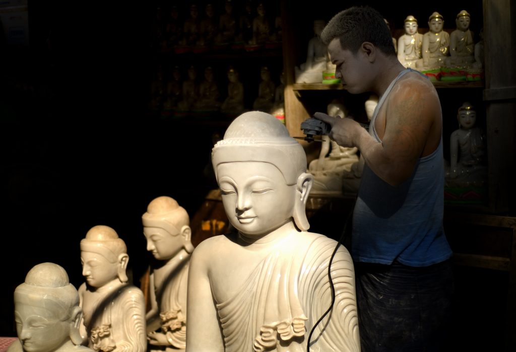 Stone sculptor carving a marble Buddha statue in Mandalay, Myanmar