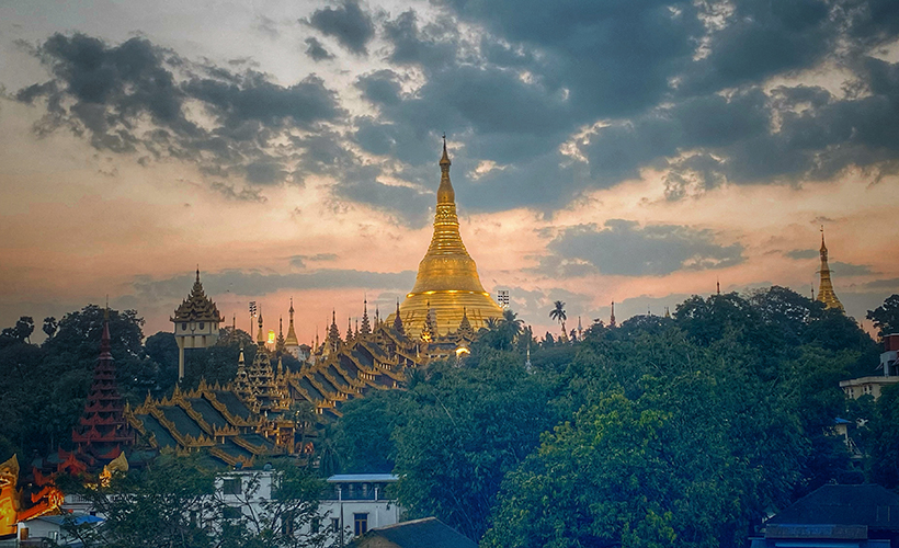 Shwedagon Pagoda at sunset in Yangon Myanmar with golden stupa glowing under dramatic evening sky